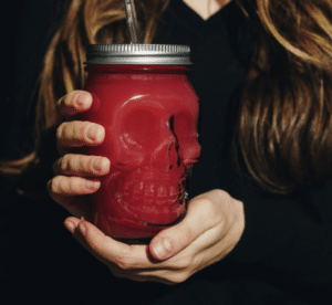 Lady holding a daiquiri in a glass skull cup for halloween